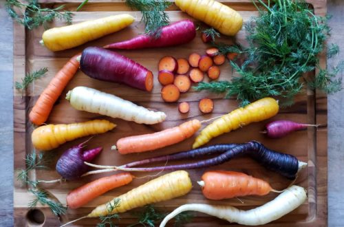 rainbow carrots on a cutting board with sprigs of fresh dill around them