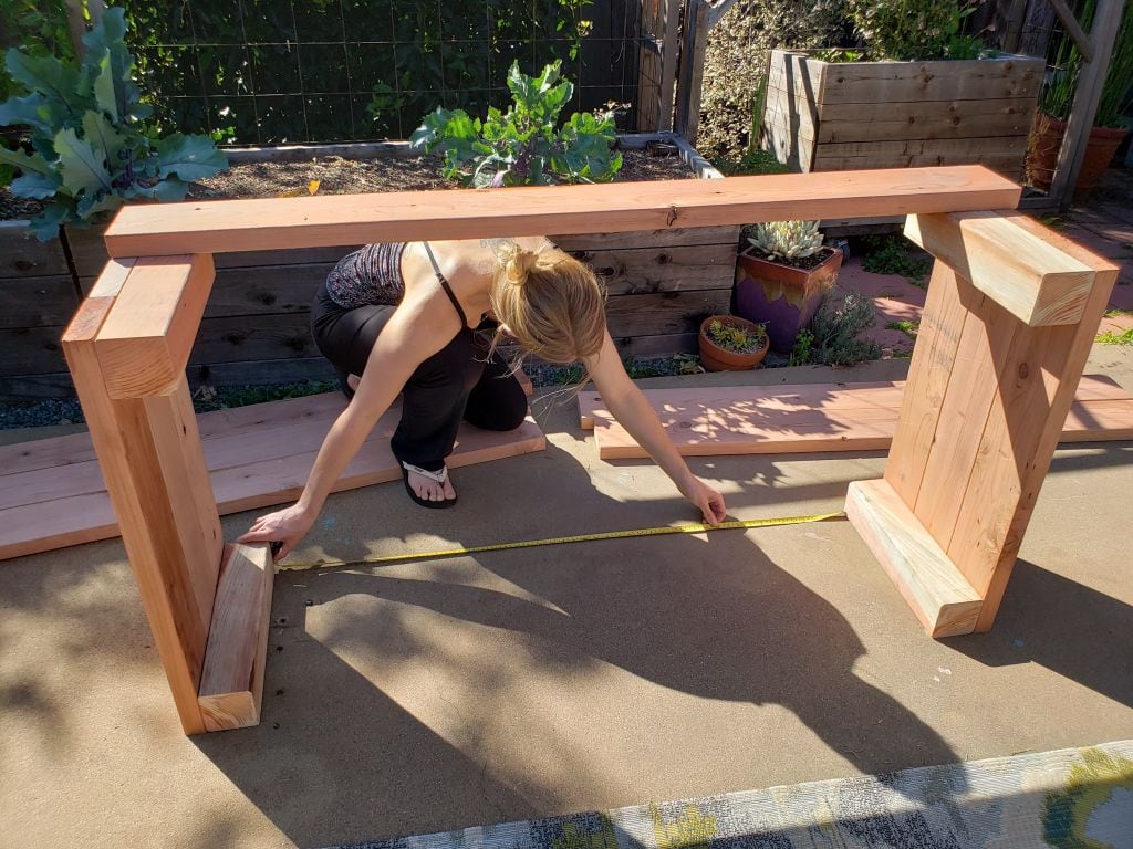 A photo of DeannaCat on the patio, measuring boards for the raised garden bed.